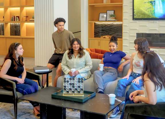 A group of people are sitting around a table in the amenities center at Era in Denton, TX
