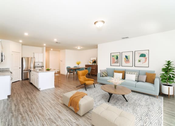 a living room with contemporary furnitures, decors, white walls and hardwood flooring