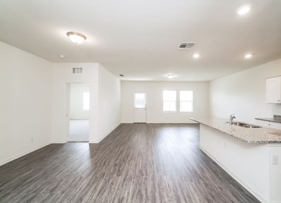 the modern living room and kitchen with white walls, windows a granite countertop