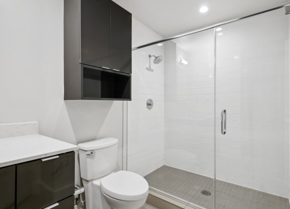 Bathroom with towel cabinet over toilet and a large walk-in shower at Mid Elm Lofts in Dallas, TX