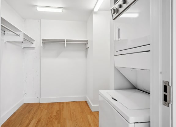 Spacious walk-in closet with a stacked washer and dryer and polished wood floors at Mid Elm Lofts in Dallas, TX