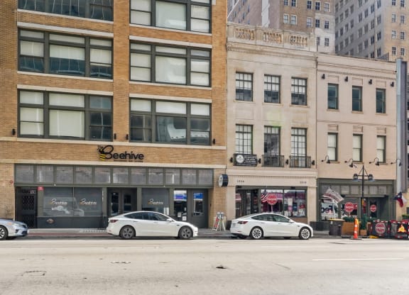 View from across the street of the Mid Elm Lofts Building with retail spots around at Mid Elm Lofts in Dallas, TX