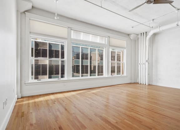 View of large living room with urban accents, polished wood floors and large windows at Mid Elm Lofts in Dallas, TX