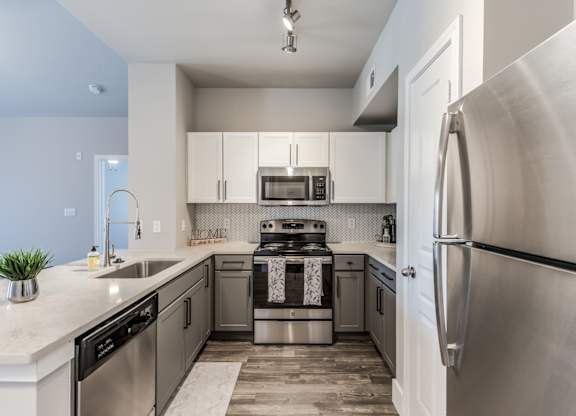 A2 model kitchen with stainless steel appliances, quartz counters, and white cabinets at Asheville at Spring Branch apartments in Houston, TX
