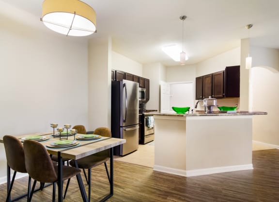 a dining area with a table and chairs and a kitchen in the background