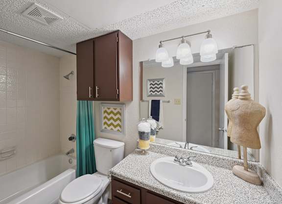 A bathroom with a white sink, brown cabinets, and a white toilet.