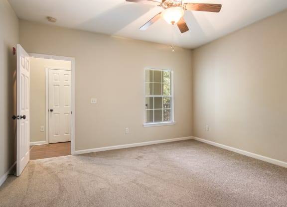 Empty bedroom with soft carpet floor and natural light at Angel Landing apartments in Pensacola, FL