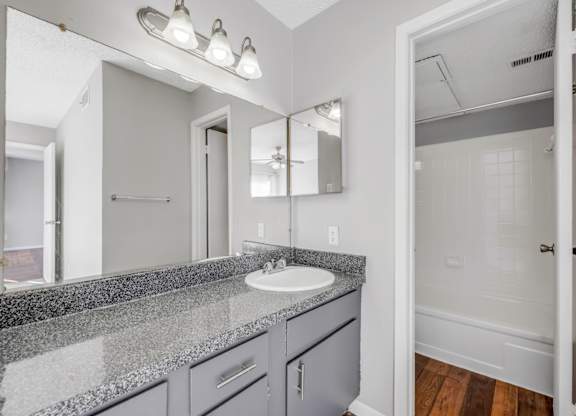 A bathroom with a sink, mirror, and lighting fixture.