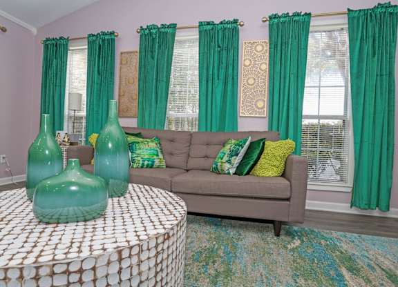 A clubhouse with a grey couch and green curtains at The Marq in Shreveport, LA