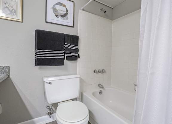 A white toilet sits next to a bathtub in a cypress bathroom at The Marq in Shreveport, LA