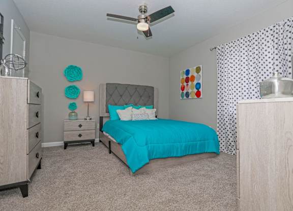 A bedroom with a bed, dresser, and ceiling fan at The Marq in Shreveport, LA