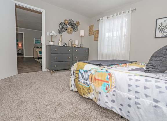 A cypress bedroom with a bed, dresser, and mirror at The Marq in Shreveport, LA