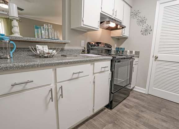 A cypress kitchen with white cabinets and a grey counter top at The Marq in Shreveport, LA