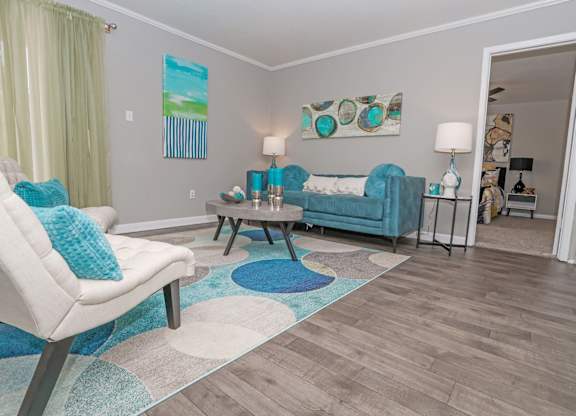 A cypress living room with a white chair and a blue couch at The Marq in Shreveport, LA