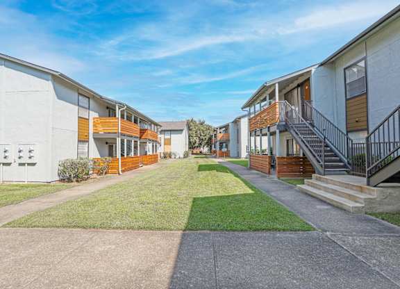 A row of modern apartment buildings with a clear blue sky above at The Marq in Shreveport, LA