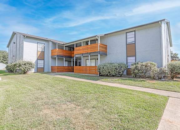 A modern two-story apartment building with a white exterior and a balcony on the second floor and patio on the first floor at The Marq apartments in Shreveport, LA