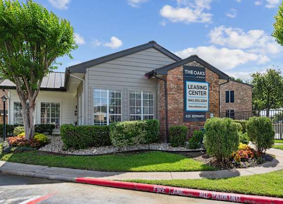 The Oaks of Denton Leasing Office is surrounded by lush hedges and lawns in Denton, TX