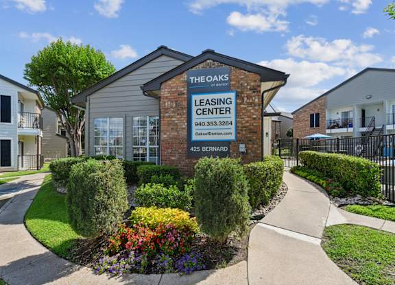 The Oaks of Denton Leasing Office is surrounded by paved paths and lush landscaping in Denton, TX
