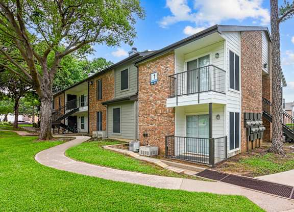 A brick apartment building with a green lawn in front.