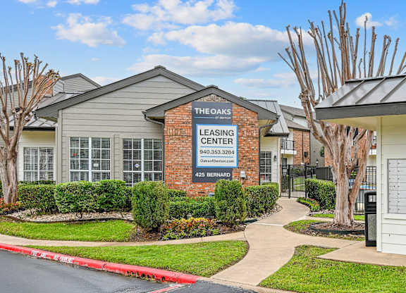 The Oaks Leasing Center is a brick building with a sign on the front.