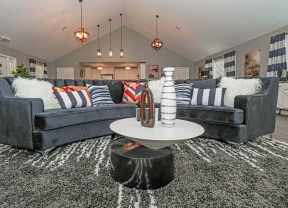 A modern clubhouse with a grey sofa and a round coffee table at Orleans Square in Shreveport, LA
