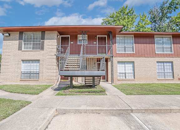 A two-story apartment building with a red roof and a stairway to the second floor at Orleans Square in Shreveport, LA