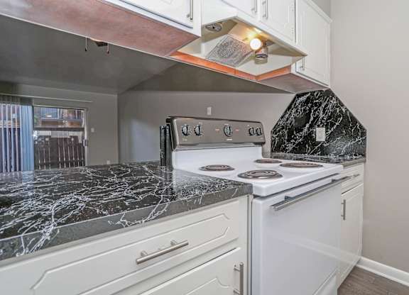 A kitchen with a white oven/stove and a dark marble countertop at Orleans Square in Shreveport, LA