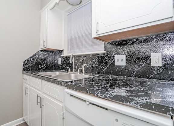 A kitchen with a marble countertop and white cabinets at Orleans Square in Shreveport, LA