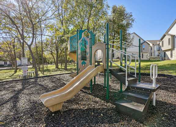 Our community playground with a slide, stairs and a climbing frame at On the Green apartments in Austin, TX