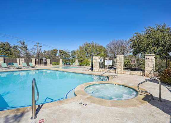Our sparkling pool with a hot tub and poolside seating at On the Green apartments in Austin, TX