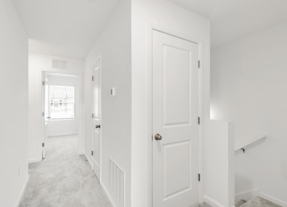 a hallway in a home with white walls and carpet