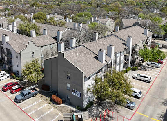 An aerial view of an apartment complex with parking and a dumpster at The Park on Preston Apartments in Dallas, TX