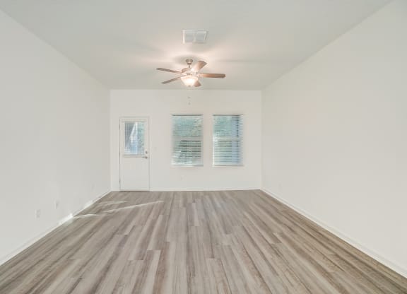 an empty living room with a ceiling fan and wood floors