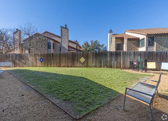 A dog park with a wooden fence and a bench at Preston Oaks Apartments in Dallas, TX.