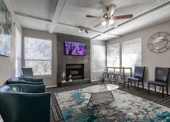 A leasing office with a fireplace, chairs, and a television at Preston Oaks Apartments in Dallas, TX.