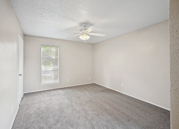 an empty bedroom with a ceiling fan