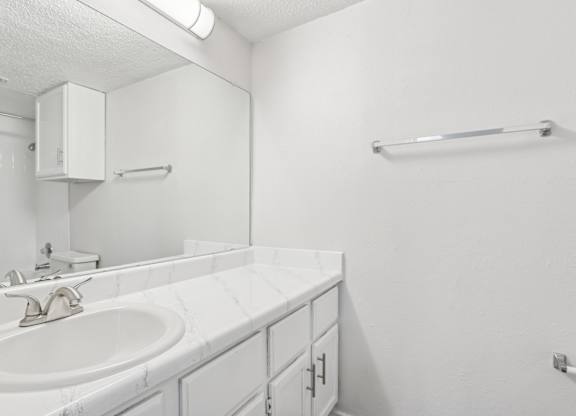 A white bathroom with a sink and a mirror.