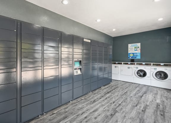 a laundry room with gray lockers and white washers and dryers