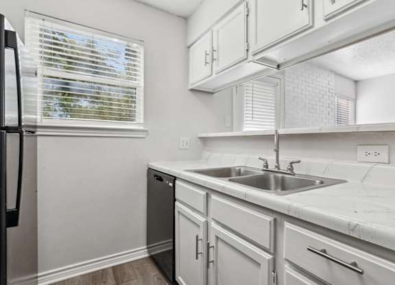 A kitchen with white cabinets and a black refrigerator.