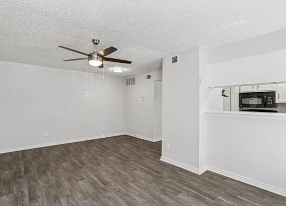 A room with a ceiling fan and wooden flooring.