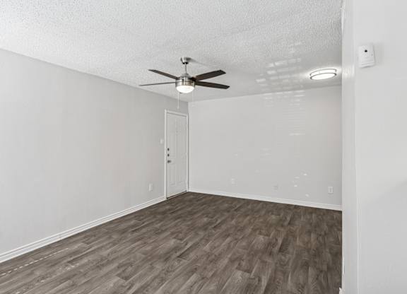 A living room with a ceiling fan and wooden flooring.