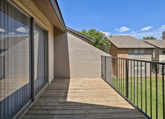 a balcony with a wooden deck and a glass sliding door