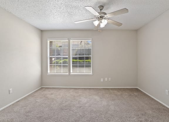 a bedroom with a ceiling fan and two windows