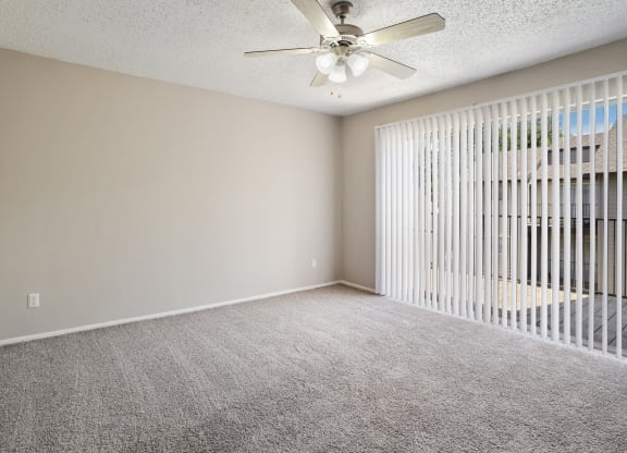 an empty bedroom with a ceiling fan and blinds