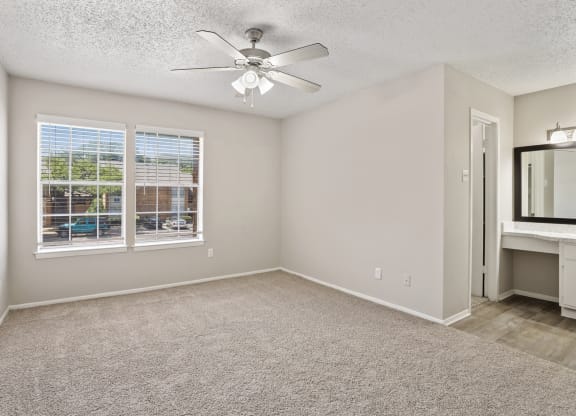 a bedroom with a large window and a ceiling fan