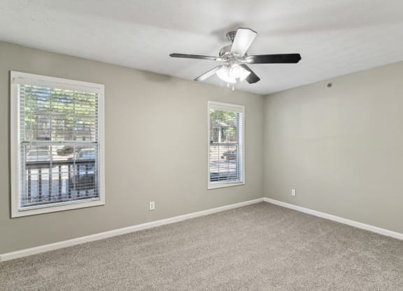 Unfurnished bedroom with plush carpeting, a ceiling fan, and windows at Oakley Run apartments in Smyrna, GA
