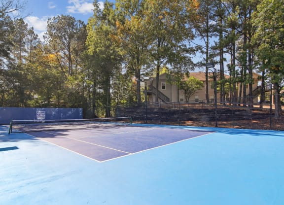 Pristine blue tennis court surrounded by trees at Oakley Run apartments in Smyrna, GA
