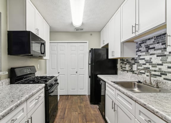Apartment kitchen with white cabinets and black appliances at Oakley Run apartments in Smyrna, GA