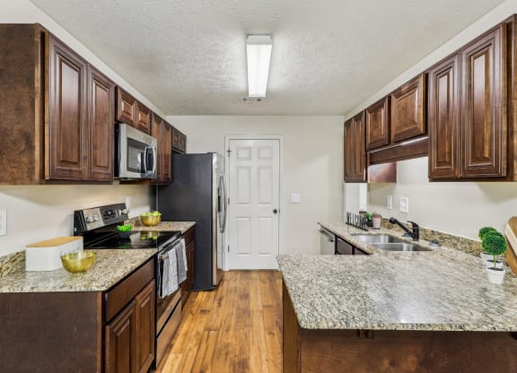 a kitchen with wooden cabinets and granite counter tops  at Grand Reserve Columbus in Columbus, GA