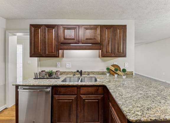 a kitchen with a granite counter top and a stainless steel sink  at Grand Reserve Columbus in Columbus, GA
